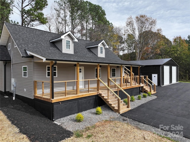 view of front facade featuring covered porch, a garage, and an outdoor structure