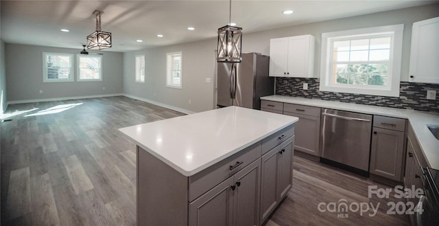 kitchen featuring decorative light fixtures, stainless steel appliances, gray cabinets, and wood-type flooring