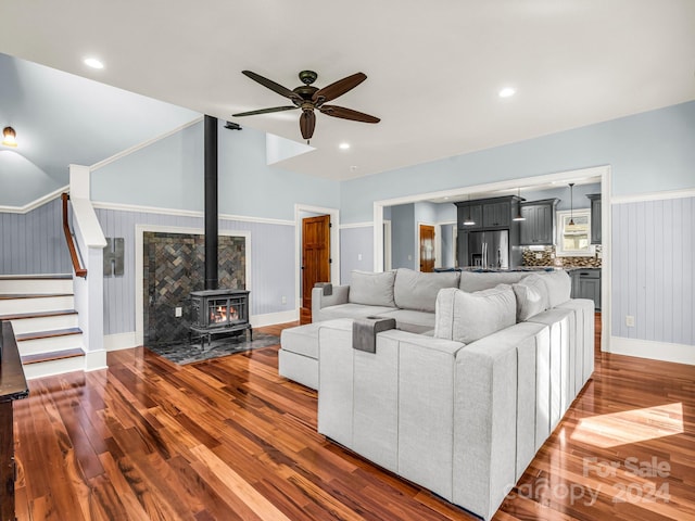 living room with a wood stove, ceiling fan, and dark wood-type flooring