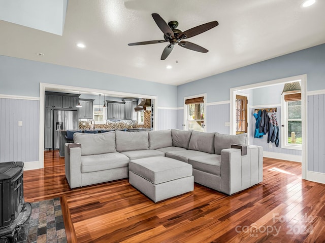 living room featuring dark hardwood / wood-style flooring, ceiling fan, and wood walls