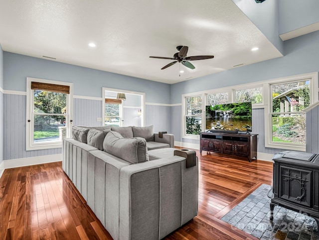 living room featuring dark hardwood / wood-style floors, ceiling fan, a wood stove, and a textured ceiling