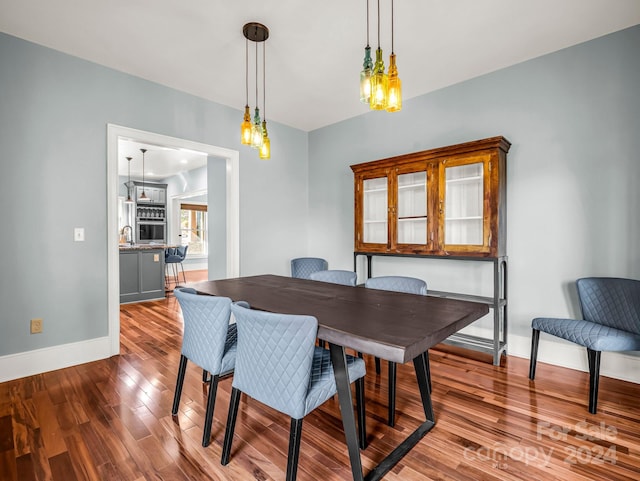 dining area with sink, a chandelier, and hardwood / wood-style flooring