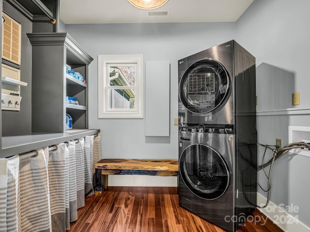 laundry area with stacked washer and dryer and dark wood-type flooring