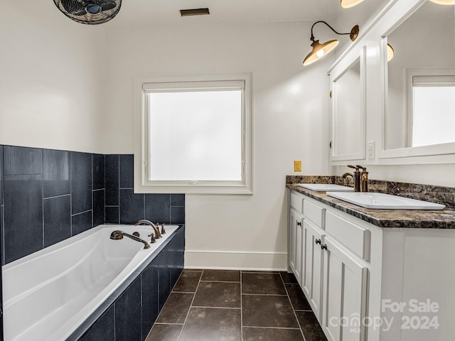 bathroom with tile patterned flooring, vanity, tiled bath, and plenty of natural light