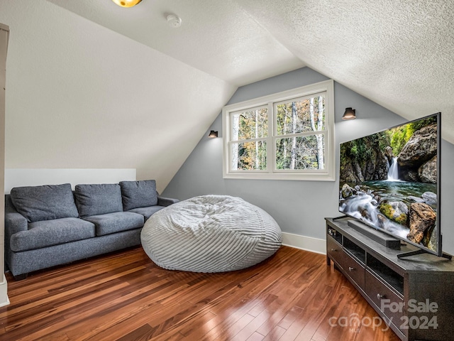 living area with a textured ceiling, dark hardwood / wood-style flooring, and vaulted ceiling