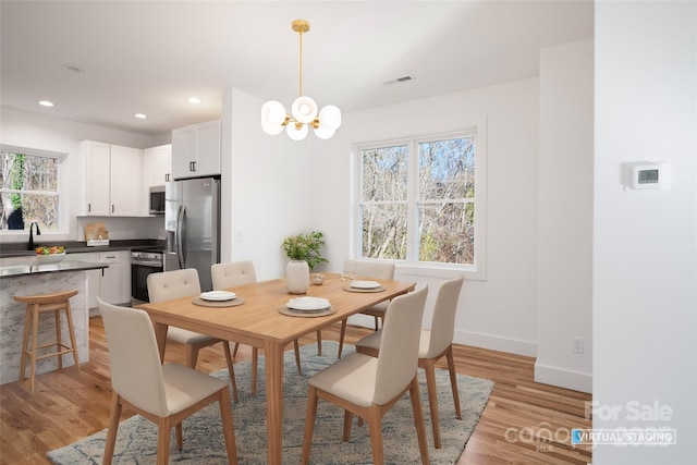 dining area featuring sink, a chandelier, and light hardwood / wood-style flooring