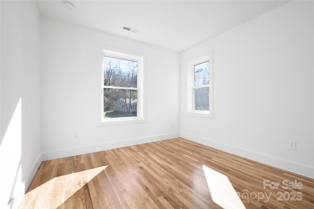 empty room with hardwood / wood-style floors and a healthy amount of sunlight