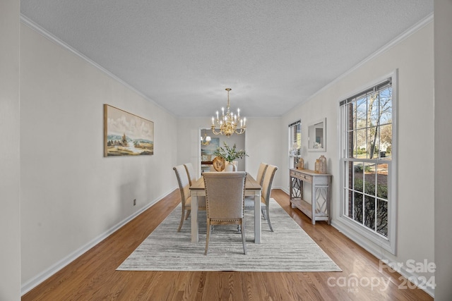 dining area featuring crown molding, light hardwood / wood-style floors, a textured ceiling, and a notable chandelier