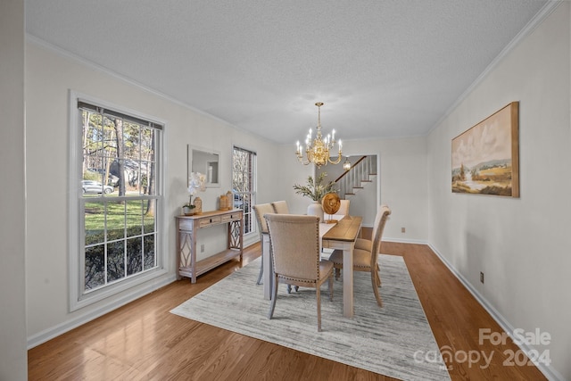 dining space featuring hardwood / wood-style floors, a textured ceiling, ornamental molding, and a notable chandelier