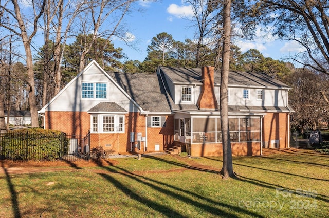 rear view of house featuring a yard and a sunroom