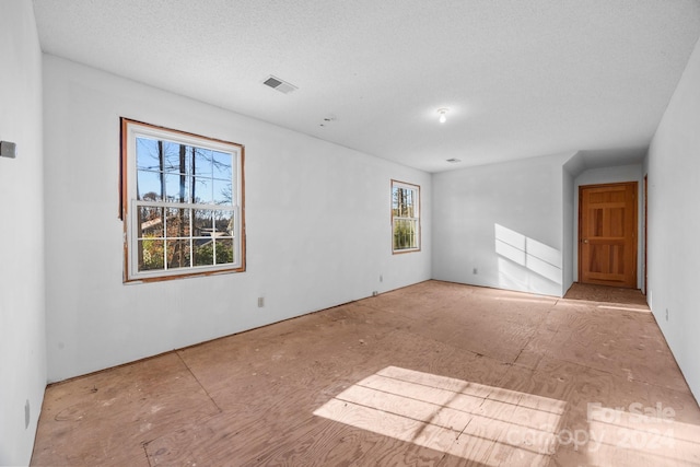 spare room featuring a textured ceiling and plenty of natural light