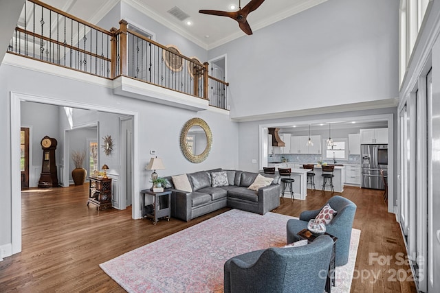 living room with ceiling fan, sink, dark hardwood / wood-style floors, and a high ceiling