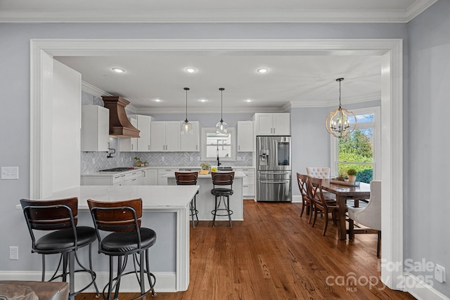 kitchen featuring a kitchen bar, white cabinetry, hanging light fixtures, and appliances with stainless steel finishes