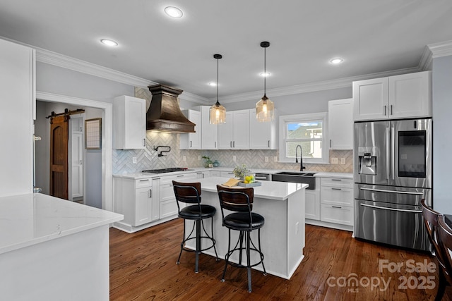 kitchen featuring custom exhaust hood, white cabinets, sink, a barn door, and stainless steel appliances