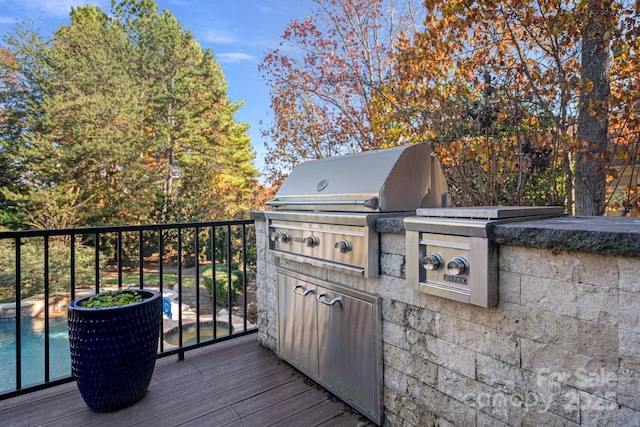 deck featuring a swimming pool, grilling area, and exterior kitchen