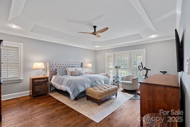 bedroom with ceiling fan, a raised ceiling, ornamental molding, and dark wood-type flooring