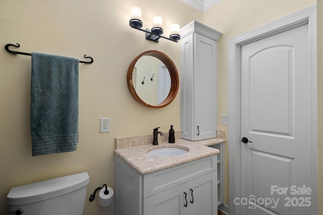 bathroom with vanity, toilet, and ornamental molding