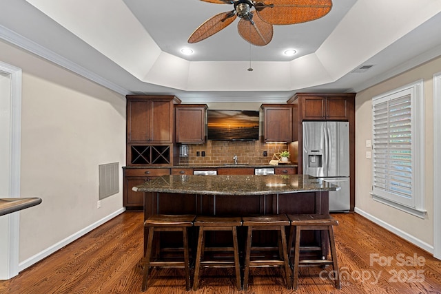 kitchen featuring dark hardwood / wood-style floors, stainless steel fridge, a kitchen breakfast bar, and sink