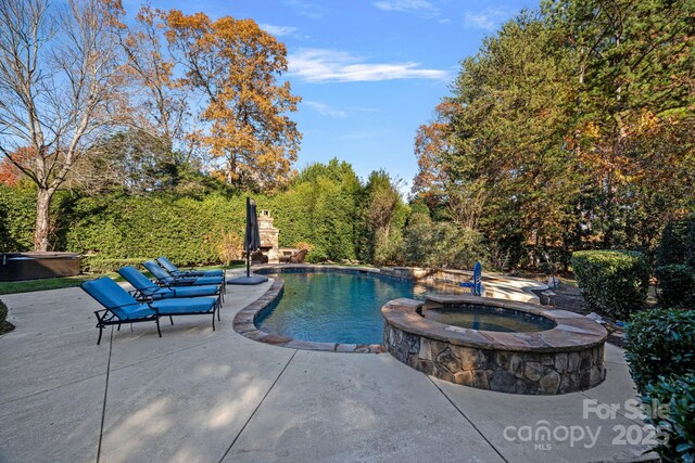 view of pool featuring an in ground hot tub and a patio