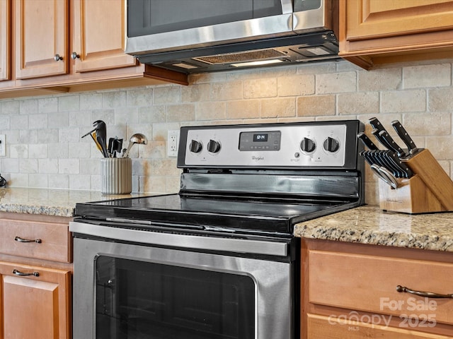 kitchen with backsplash, light stone countertops, and stainless steel appliances