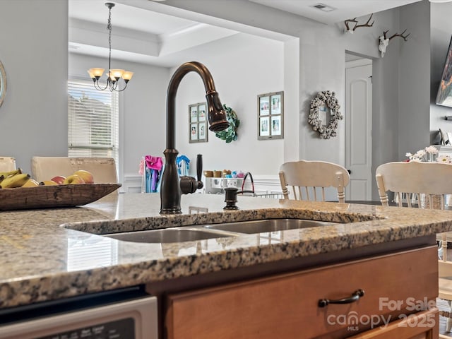 kitchen with decorative light fixtures, stone countertops, dishwasher, and a chandelier