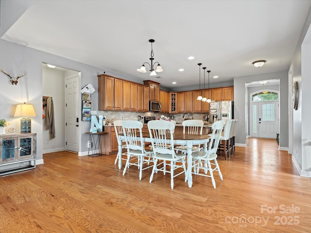 dining space with light hardwood / wood-style flooring and a notable chandelier