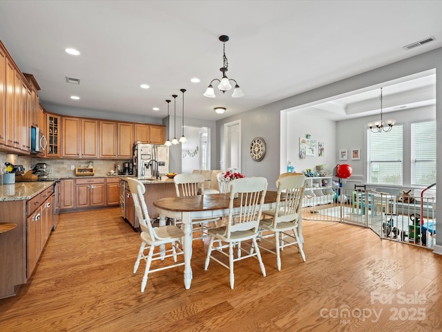 dining space with light hardwood / wood-style flooring and an inviting chandelier