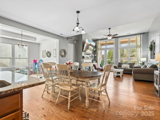 dining room featuring hardwood / wood-style floors, ceiling fan with notable chandelier, and french doors