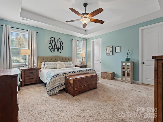 carpeted bedroom with a tray ceiling and ceiling fan