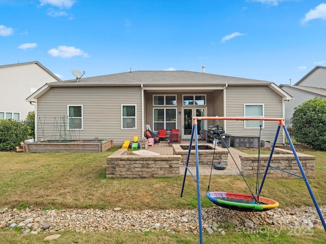 back of property featuring a playground, a lawn, and a patio