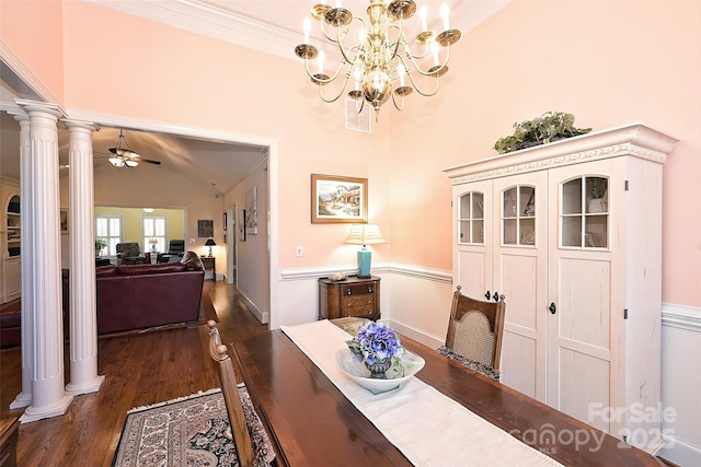 dining room featuring vaulted ceiling, dark wood-type flooring, ornamental molding, ceiling fan with notable chandelier, and ornate columns