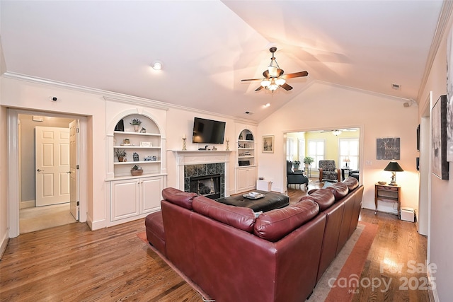 living room featuring ceiling fan, a baseboard radiator, a premium fireplace, built in features, and vaulted ceiling