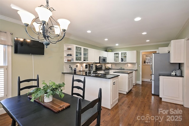 kitchen with white cabinetry, stainless steel appliances, decorative light fixtures, a chandelier, and crown molding