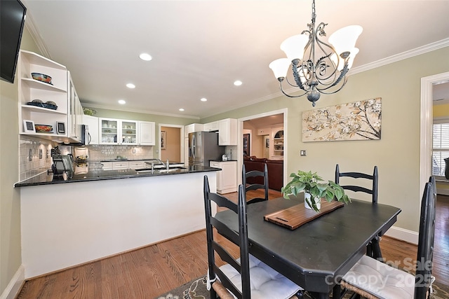 dining room featuring a notable chandelier, sink, ornamental molding, and dark hardwood / wood-style floors