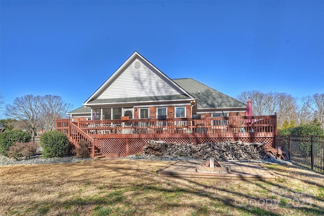 back of house featuring a lawn, an outdoor fire pit, and a wooden deck