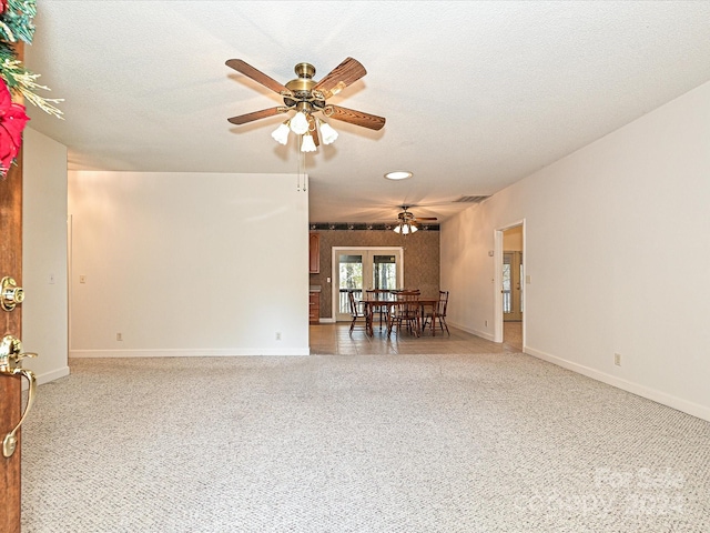 spare room featuring carpet flooring, ceiling fan, french doors, and a textured ceiling