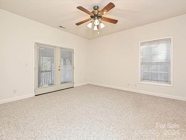 carpeted empty room with ceiling fan, french doors, and a textured ceiling