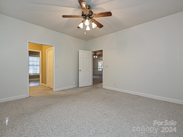 unfurnished bedroom featuring ceiling fan, light carpet, and a textured ceiling