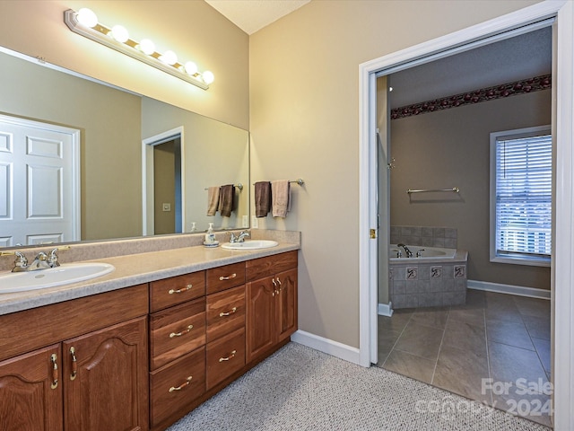 bathroom featuring tile patterned floors, tiled bath, and vanity