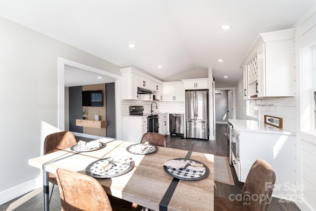 dining room with dark hardwood / wood-style flooring, vaulted ceiling, and sink