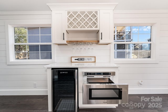 kitchen with wooden walls, light stone countertops, white cabinetry, and wine cooler