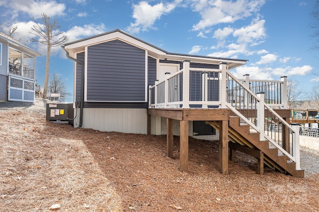 back of property with a sunroom, central AC unit, and a deck