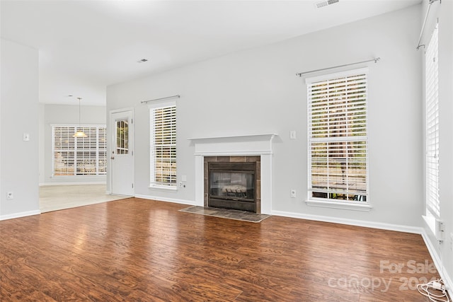 unfurnished living room featuring a tile fireplace and hardwood / wood-style flooring