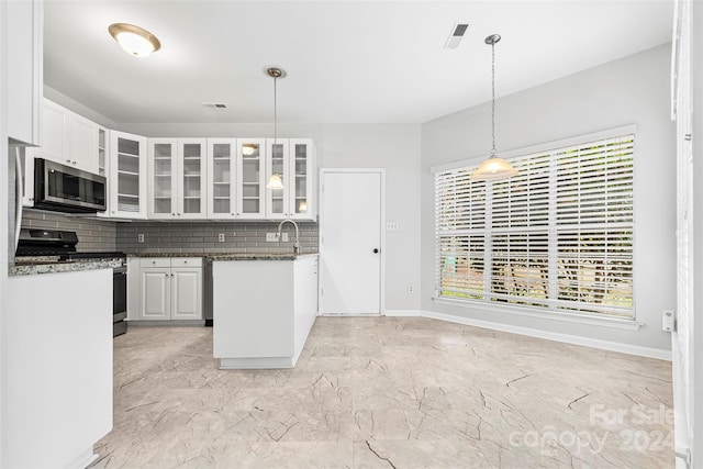 kitchen featuring stainless steel appliances, white cabinetry, tasteful backsplash, and dark stone counters