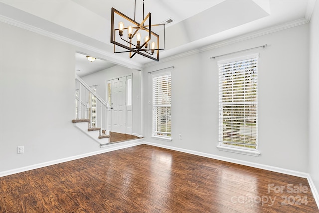 entrance foyer featuring wood-type flooring, ornamental molding, a wealth of natural light, and a notable chandelier