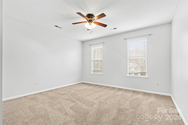 carpeted empty room featuring ceiling fan and a textured ceiling