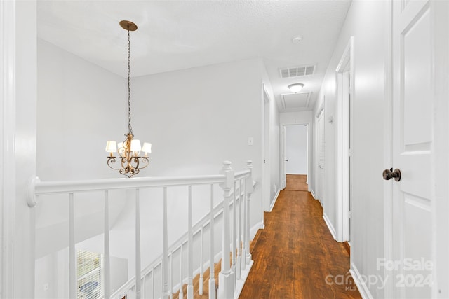 hallway with a chandelier, a textured ceiling, and dark wood-type flooring