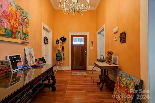 entrance foyer with hardwood / wood-style floors, crown molding, and a notable chandelier