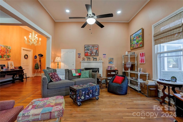 living room featuring crown molding, ceiling fan with notable chandelier, and light wood-type flooring