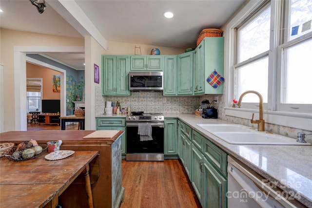 kitchen with lofted ceiling, sink, green cabinetry, light hardwood / wood-style flooring, and appliances with stainless steel finishes